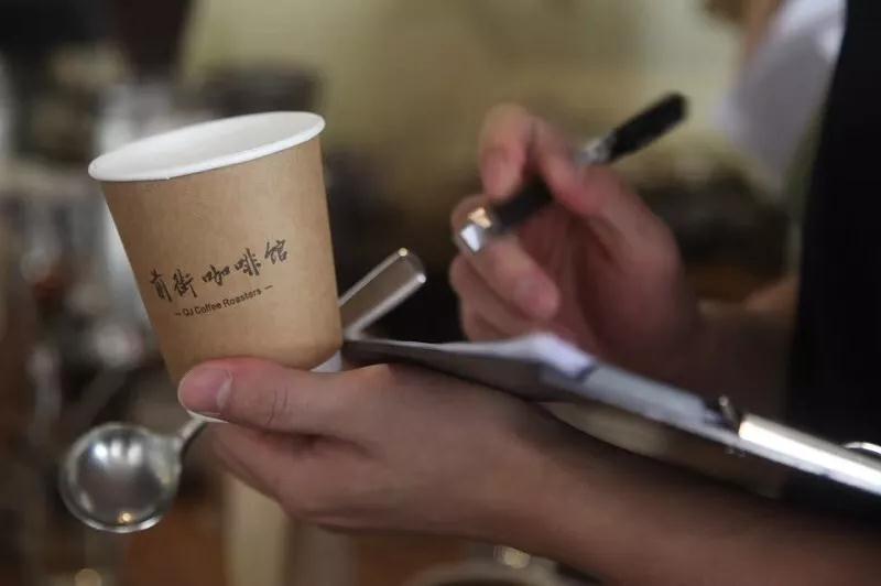 Spitting coffee into spittoon during cupping